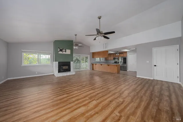 an empty room with wooden floor fireplace and windows