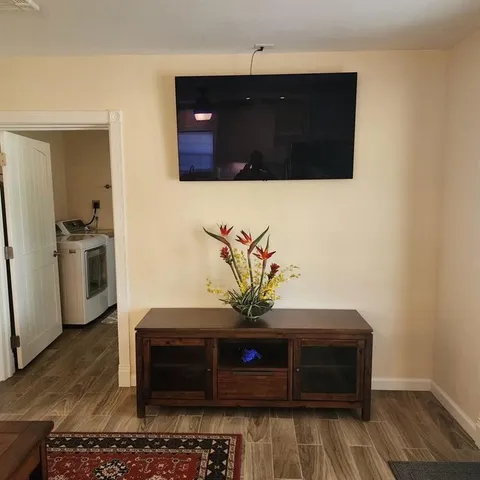 a living room with stainless steel appliances wooden cabinets and a wooden floor