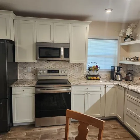 a kitchen with cabinets stainless steel appliances and wooden floor