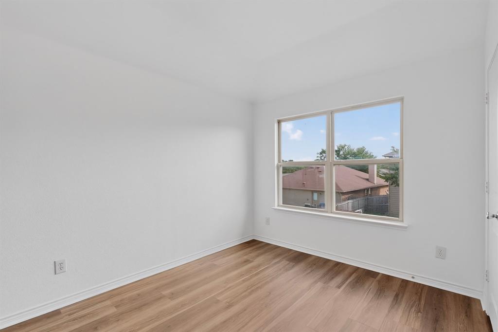 426 Harding Lane Lavon, TX 75166 - Photo 24 of 40 Bright interior space featuring a window with a neighborhood backdrop, wood-finish flooring, white baseboards, and neutral wall tones