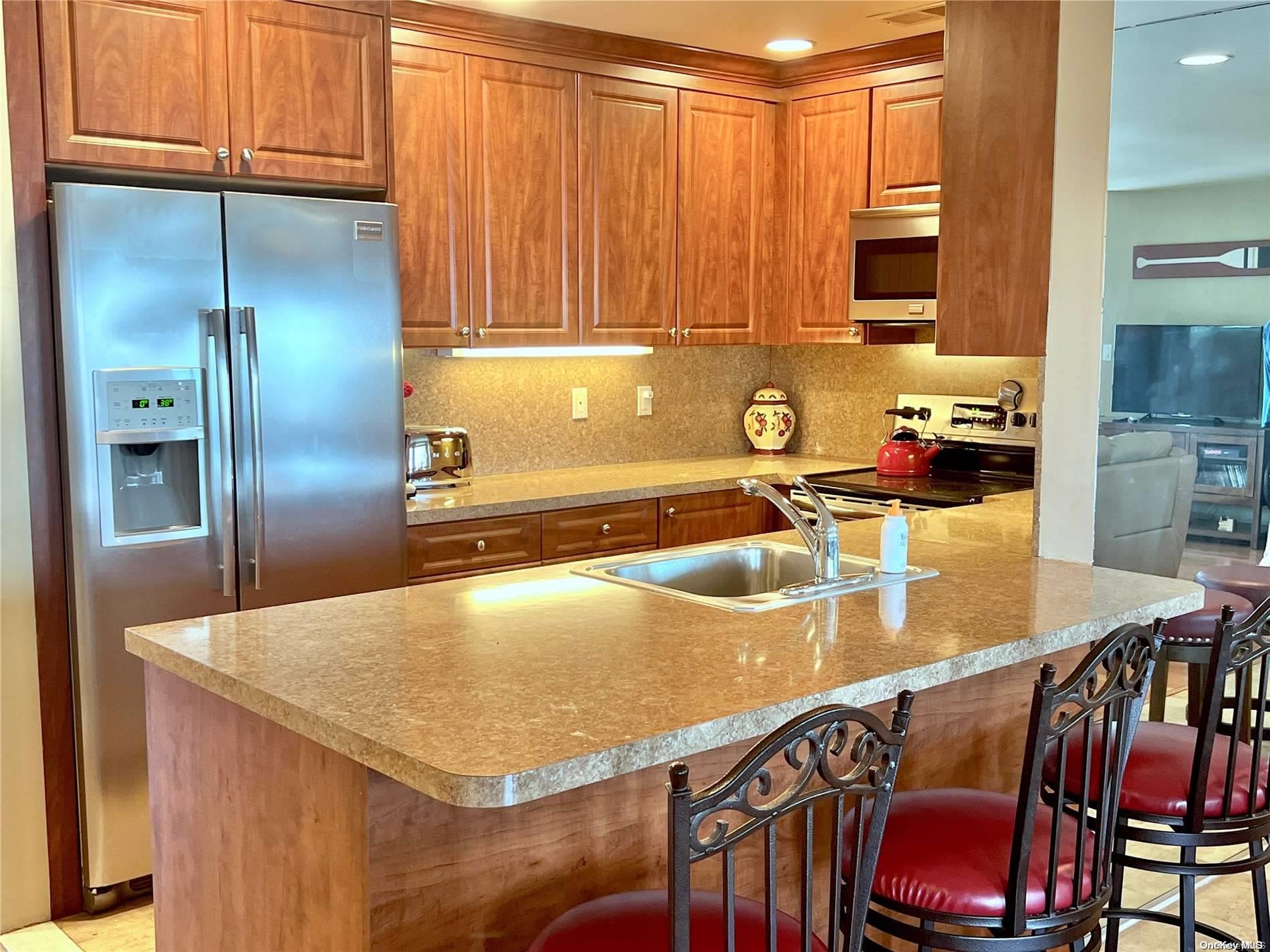 813 Shore Road Long Beach, NY 11561 - Photo 6 of 33 a kitchen with stainless steel appliances granite countertop a refrigerator a stove and a sink with wooden cabinets