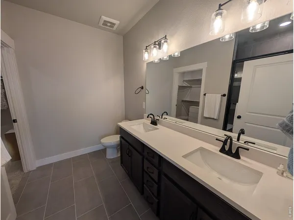 a bathroom with a double vanity sink a toilet and a mirror