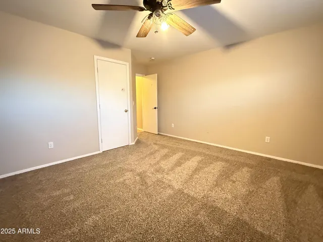 an empty room with a ceiling fan and window