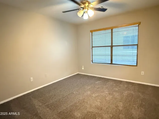 an empty room with a chandelier fan and windows