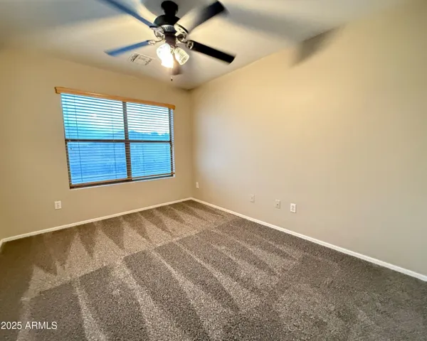 an empty room with windows and fan