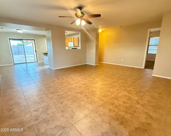 a view of an empty room with a chandelier fan and a window