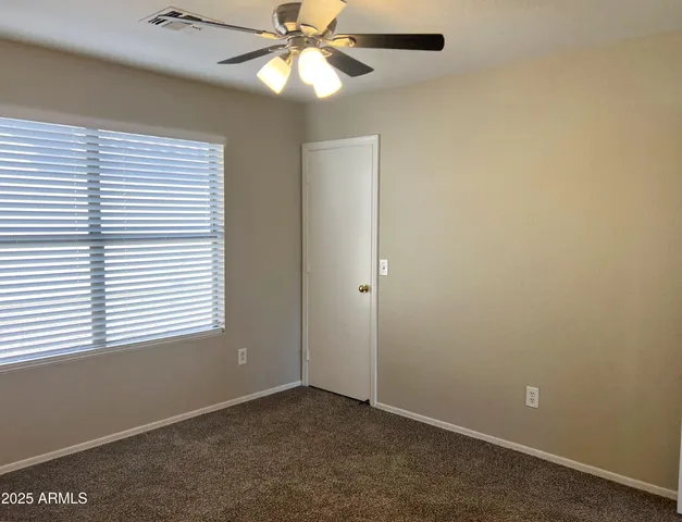 an empty room with a window and a fan