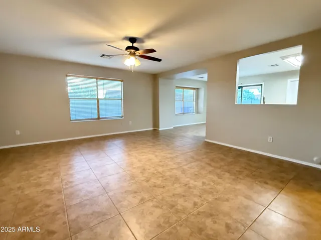 an empty room with windows and chandelier fan