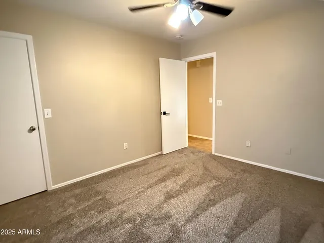 a view of an empty room and chandelier fan