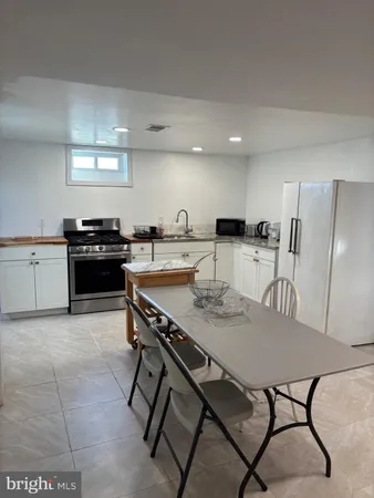 a kitchen with stainless steel appliances granite countertop a table chairs and a refrigerator