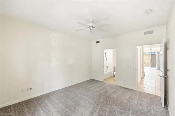 an empty room with a ceiling fan and carpet