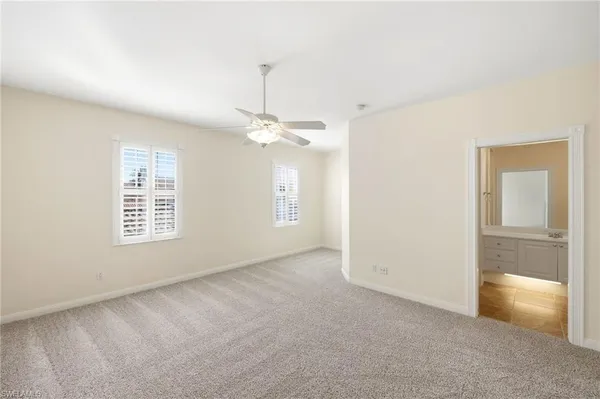 an empty room with chandelier fan and windows