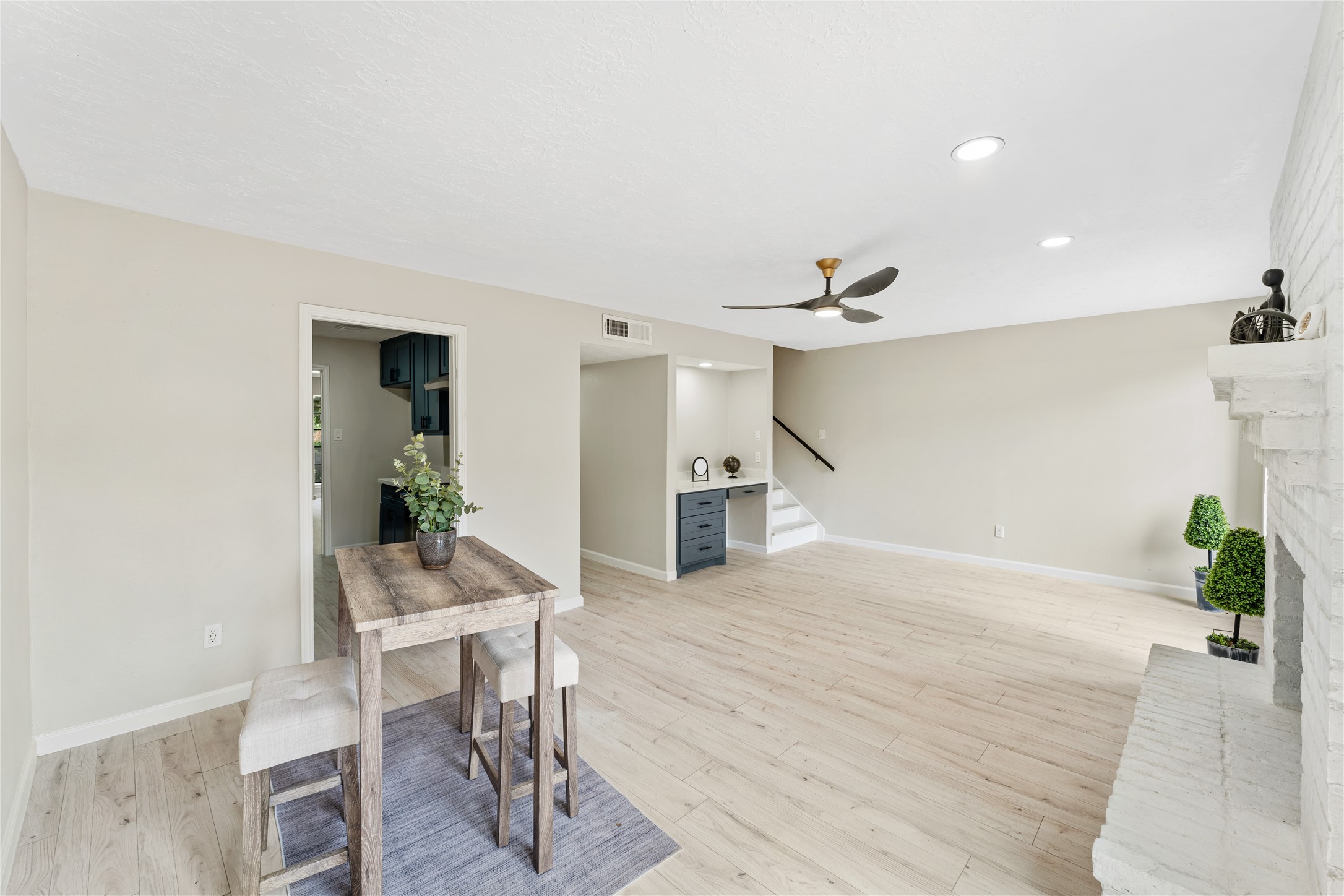 9425 Fondren Road Houston, TX 77074 - Photo 13 of 29 Spacious and bright family room, featuring light wood flooring, a modern ceiling fan, a built in desk and a cozy brick fireplace.
