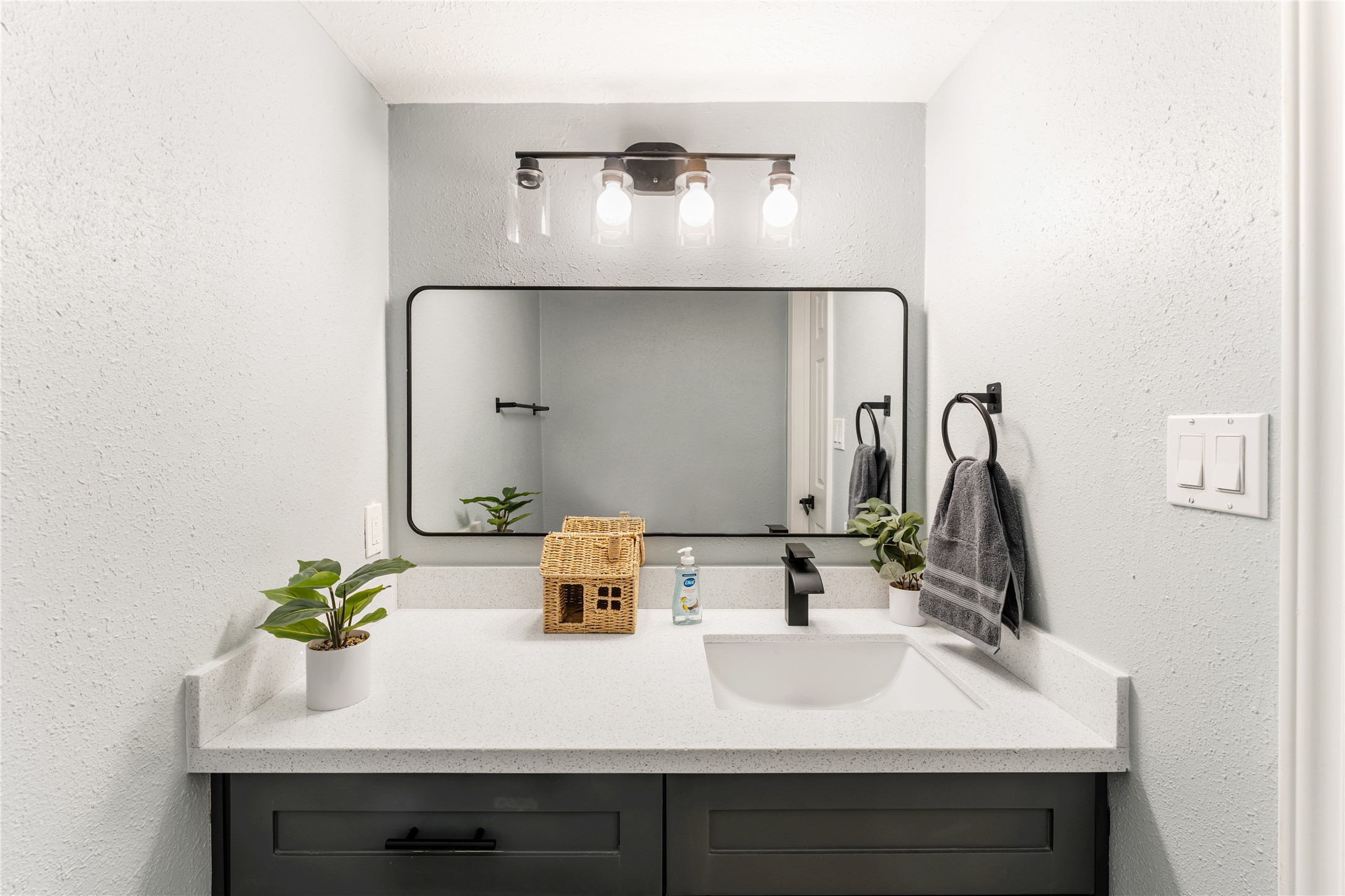 9425 Fondren Road Houston, TX 77074 - Photo 19 of 29 The conveniently located half bathroom features a modern vanity with a sleek black faucet, a framed mirror, and stylish lighting. The gray walls and countertop create a clean, contemporary look.