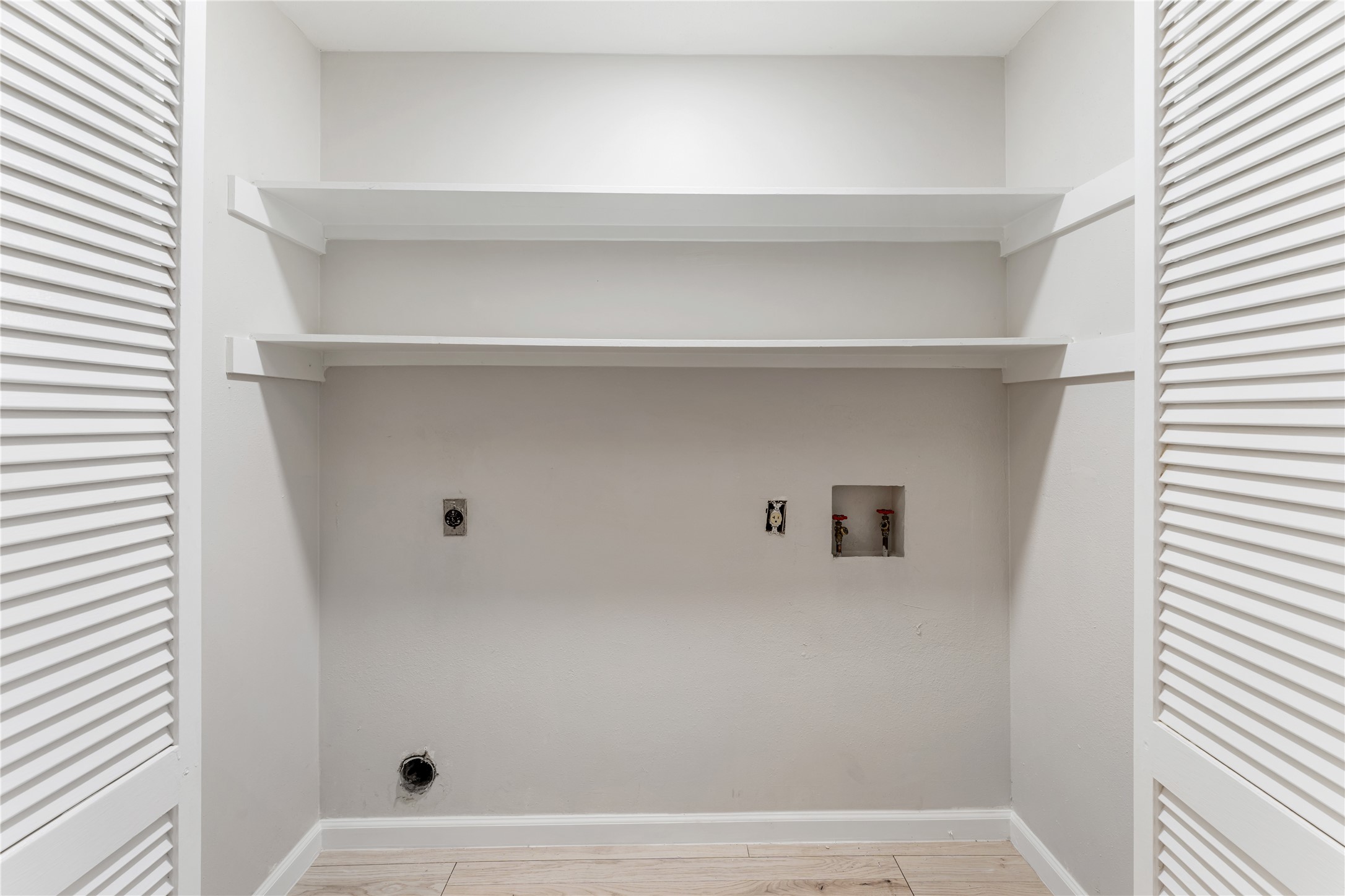 9425 Fondren Road Houston, TX 77074 - Photo 24 of 29 Conveniently located on the second floor, the laundry area features two shelves for storage and has louvered doors, offering a neat and organized space for laundry needs.