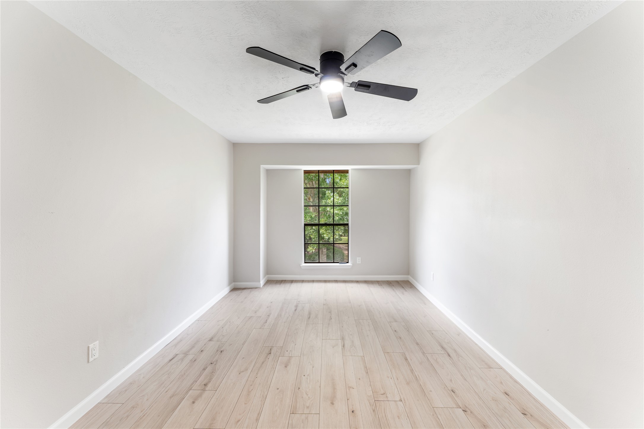 9425 Fondren Road Houston, TX 77074 - Photo 26 of 29 This secondary bedroom is ample and features a large window with a black frame, allowing natural light in. It includes a modern ceiling fan, creating a bright and airy atmosphere, ideal for a bedroom or office.