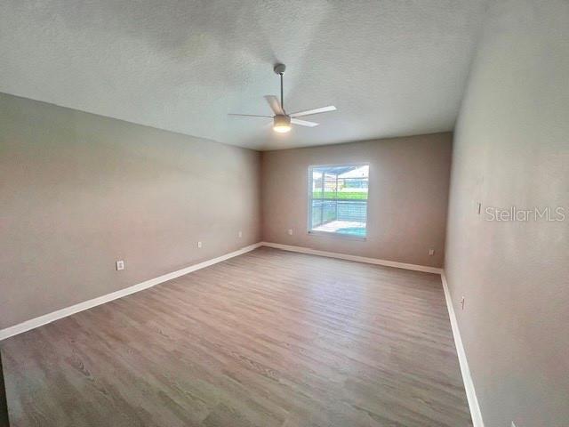 2749 Callaway Lane Kissimmee, FL 34744 - Photo 7 of 30 an empty room with wooden floor ceiling fan and windows