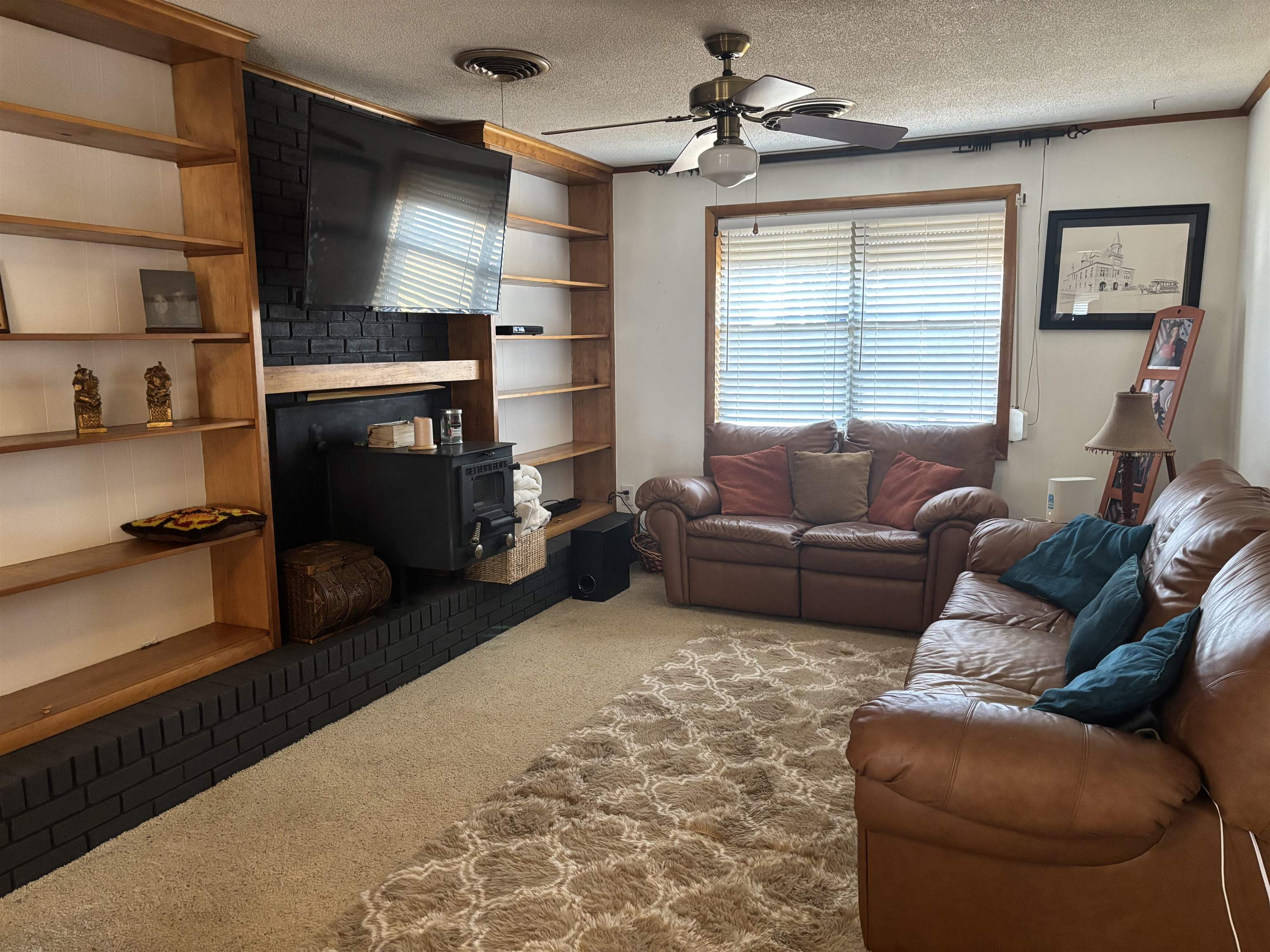 496 Chalmers Road Memphis, TN 38120 - Photo 3 of 20 Carpeted living room with ceiling fan, a wood stove, and a textured ceiling