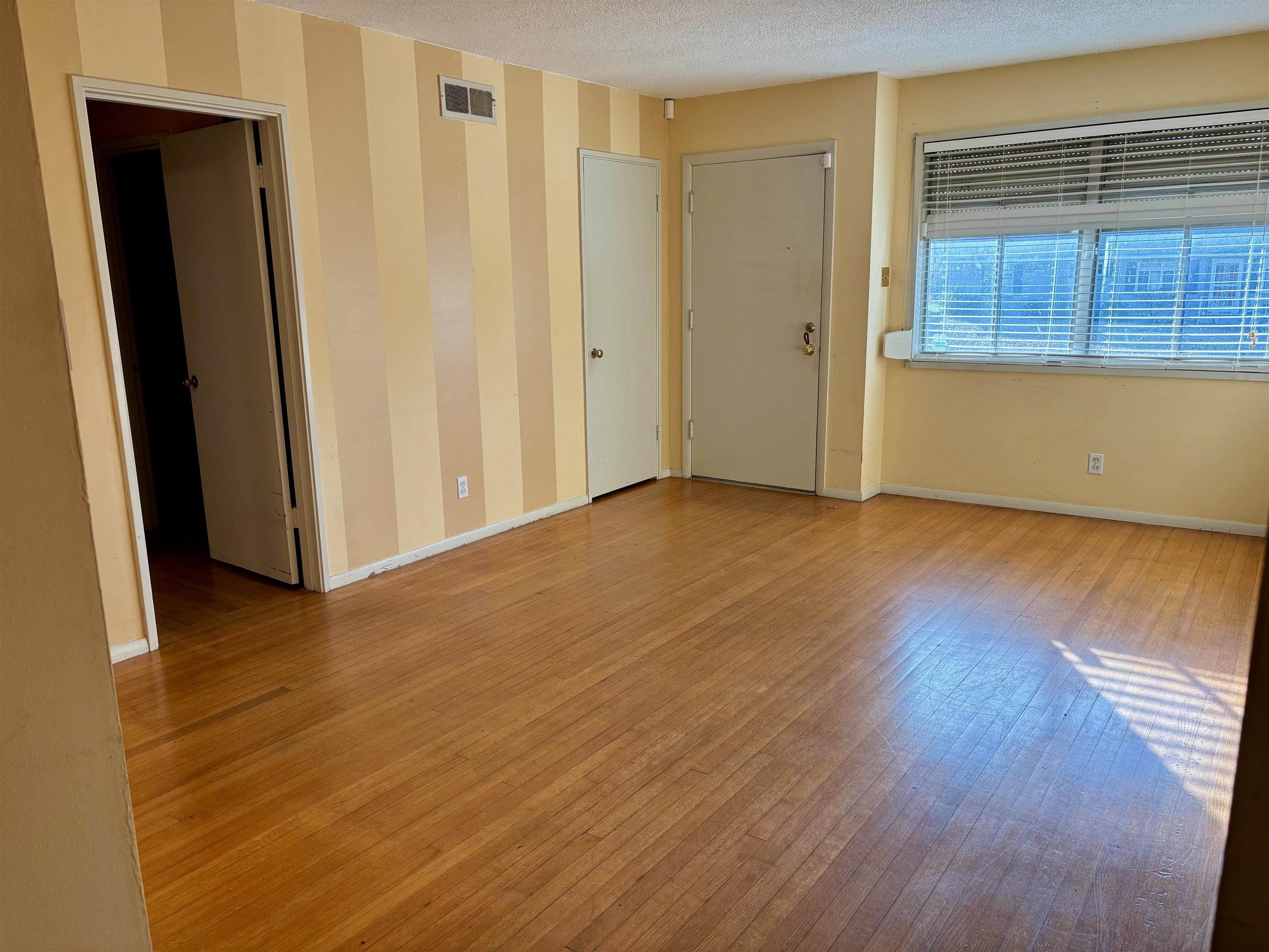 496 Chalmers Road Memphis, TN 38120 - Photo 6 of 20 Unfurnished room with a textured ceiling, baseboards, visible vents, and wood finished floors