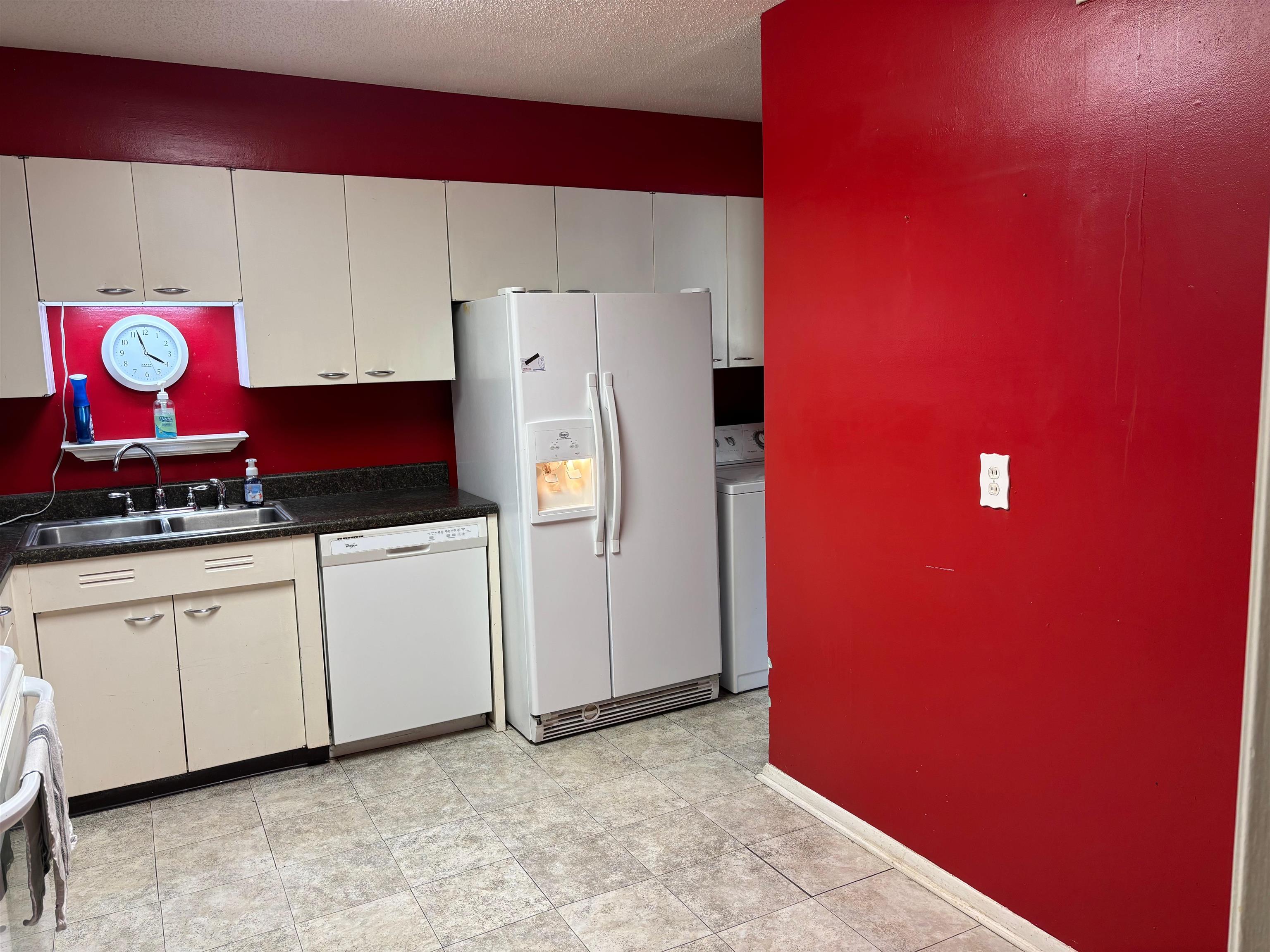 496 Chalmers Road Memphis, TN 38120 - Photo 10 of 20 Kitchen featuring washer / dryer, dark countertops, white appliances, a textured ceiling, and a sink