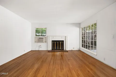an empty room with wooden floor and a fireplace