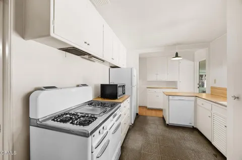 a kitchen with white cabinets and appliances