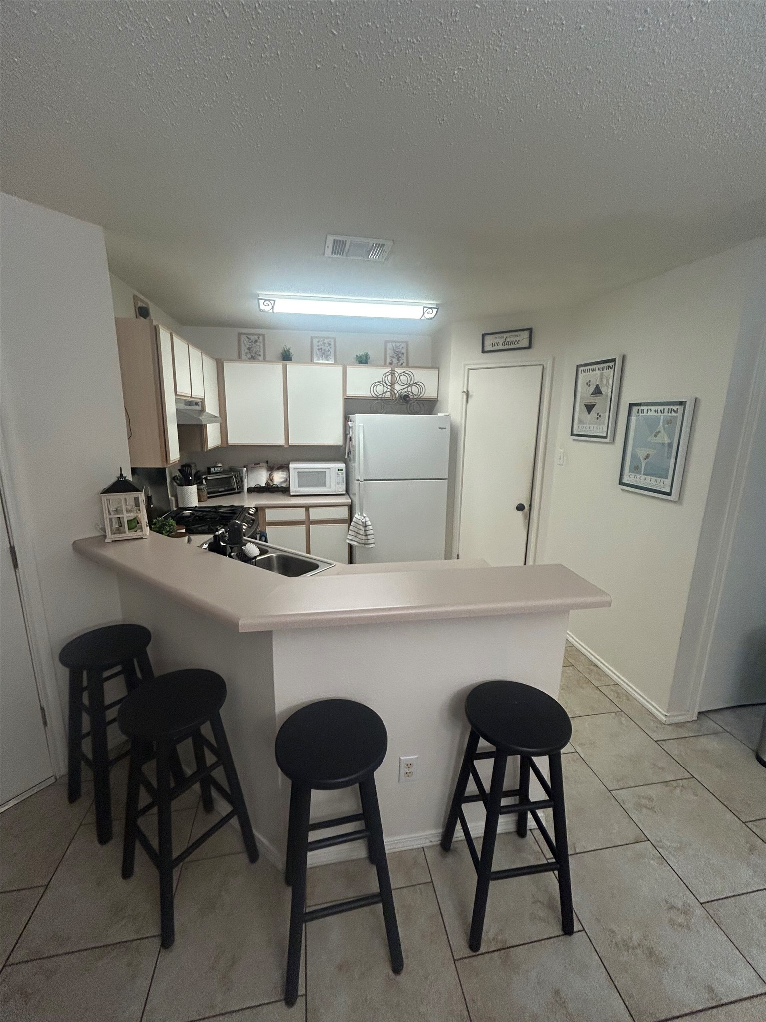 7229 Aldea Drive, Unit B Austin, TX 78745 - Photo 12 of 13 a kitchen with a table chairs microwave and cabinets