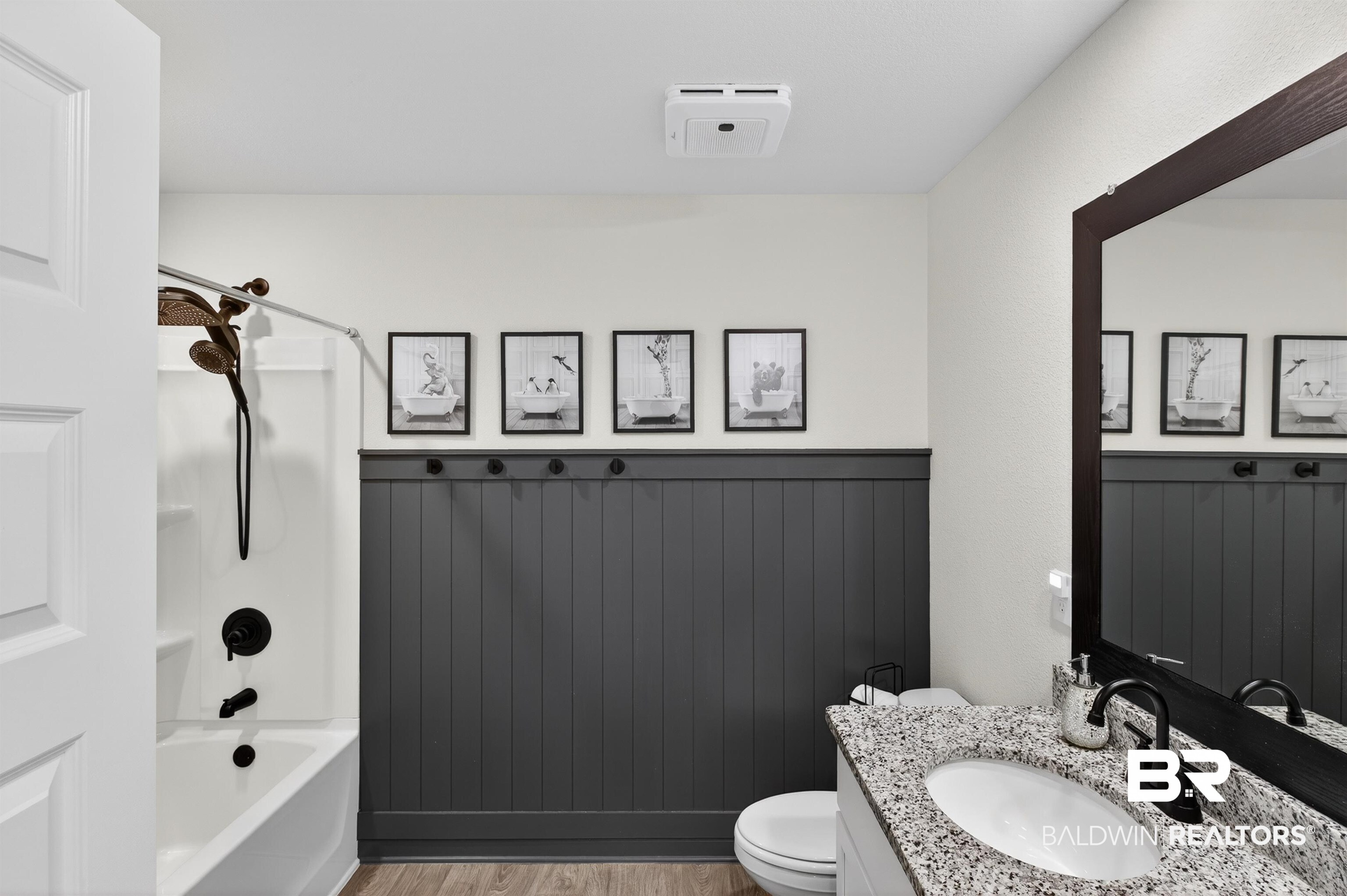 3213 Camino Real Loop Lillian, AL 36549 - Photo 52 of 61 Bathroom featuring a white bathtub with dark bronze fixtures, dark gray wainscoting, and wood-finish flooring