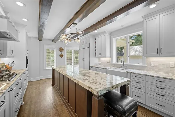 a kitchen with granite countertop a sink appliances cabinets and wooden floor