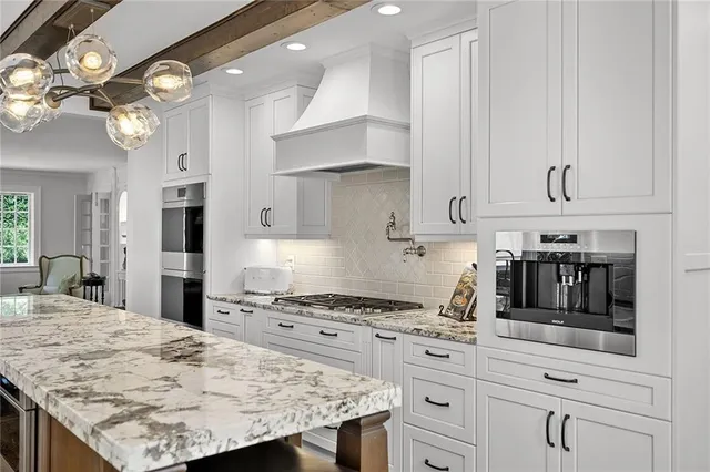 a kitchen with granite countertop a stove a oven a refrigerator and white cabinets with wooden floor