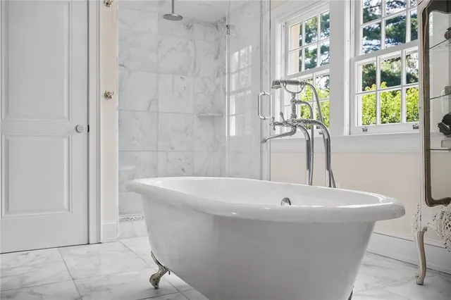a white bath tub sitting in a bathroom next to a window