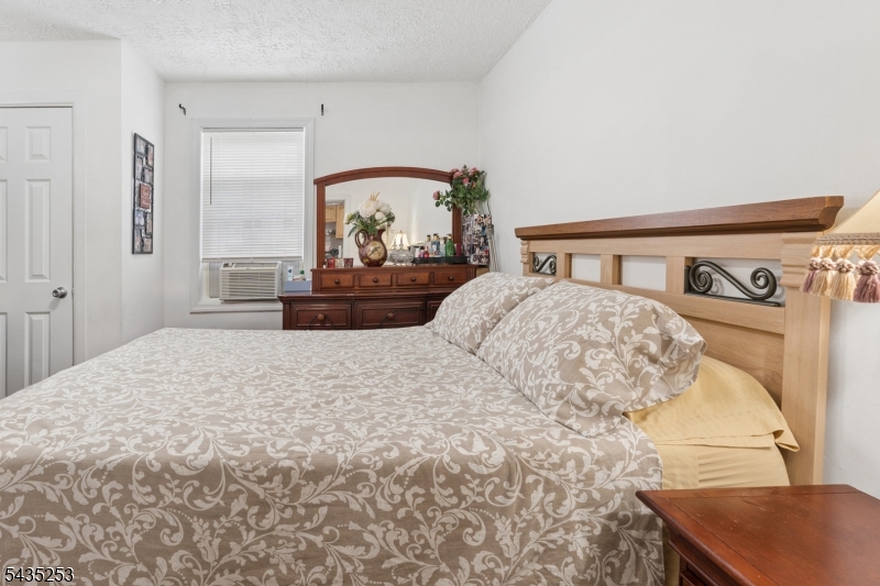 61 Union Street, Unit 2 Lodi, NJ 07644 - Photo 6 of 8 a bedroom with a bed and a dresser with mirror