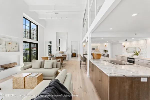 a living room with kitchen island furniture a rug kitchen view and a large window