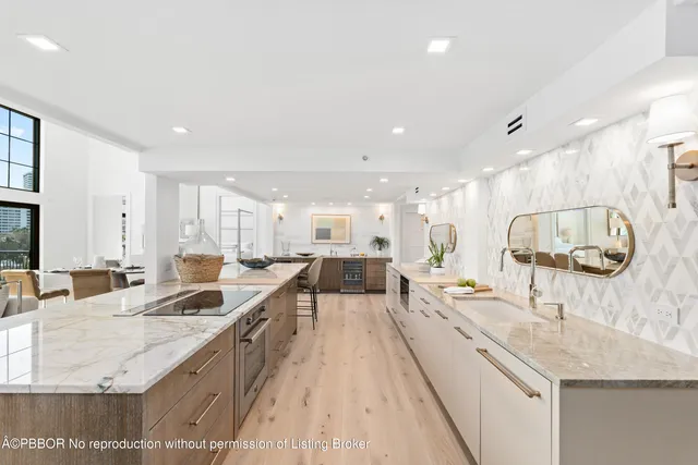 a large kitchen with a large counter top a sink a window and living room view