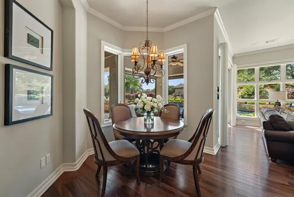 a kitchen with stainless steel appliances granite countertop a stove a refrigerator a kitchen island a dining table and chairs with wooden floor