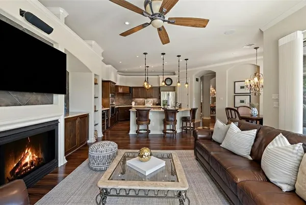 a kitchen with stainless steel appliances kitchen island granite countertop a table chairs a sink dishwasher a microwave oven and a dining table with wooden floor