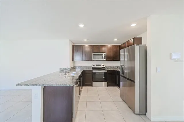 a kitchen with stainless steel appliances granite countertop a refrigerator a sink a stove and oven