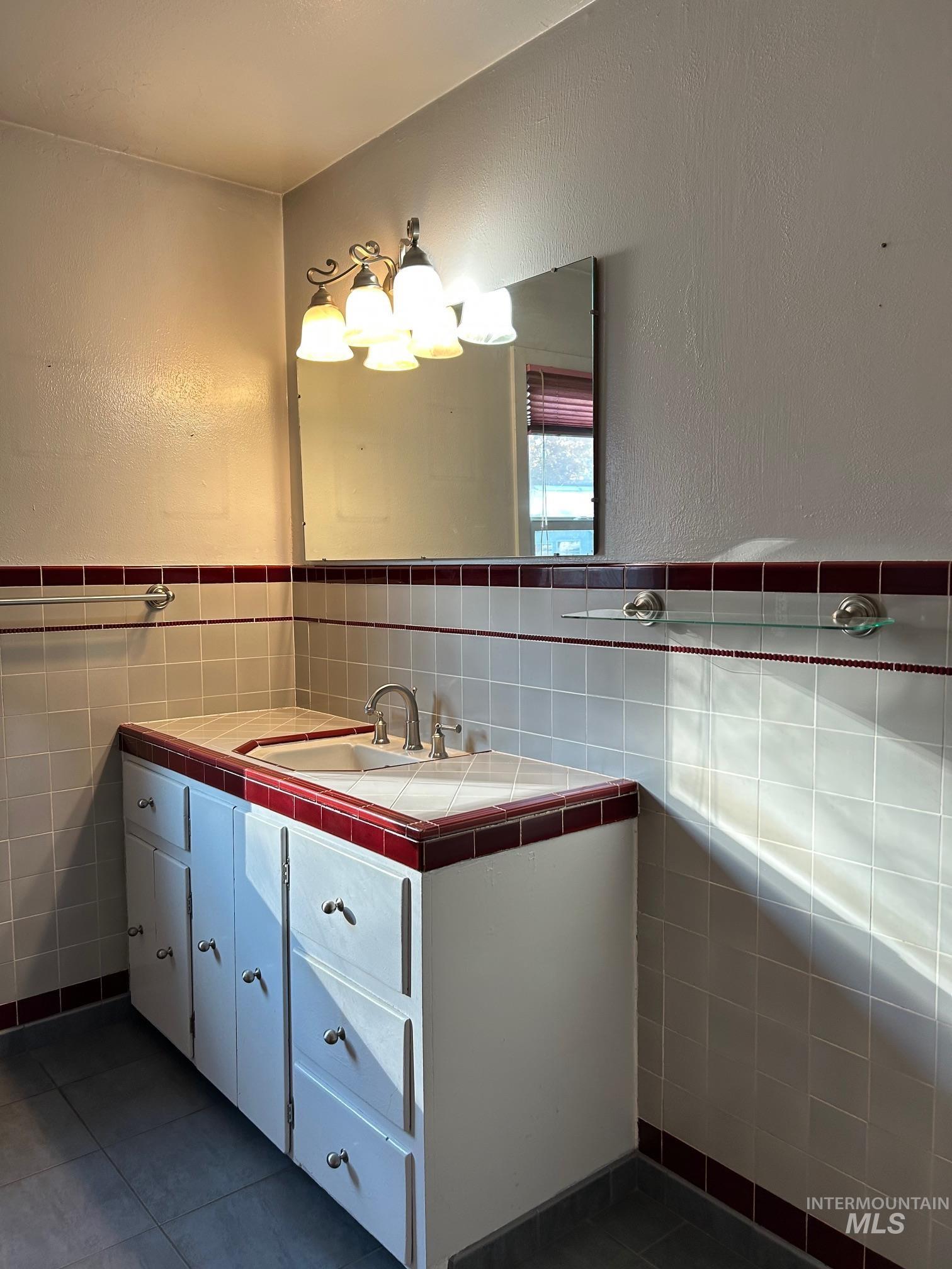 112 17th Avenue Lewiston, ID 83501 - Photo 23 of 40 Bath featuring a textured wall, tile walls, vanity, dark tile patterned flooring, and wainscoting