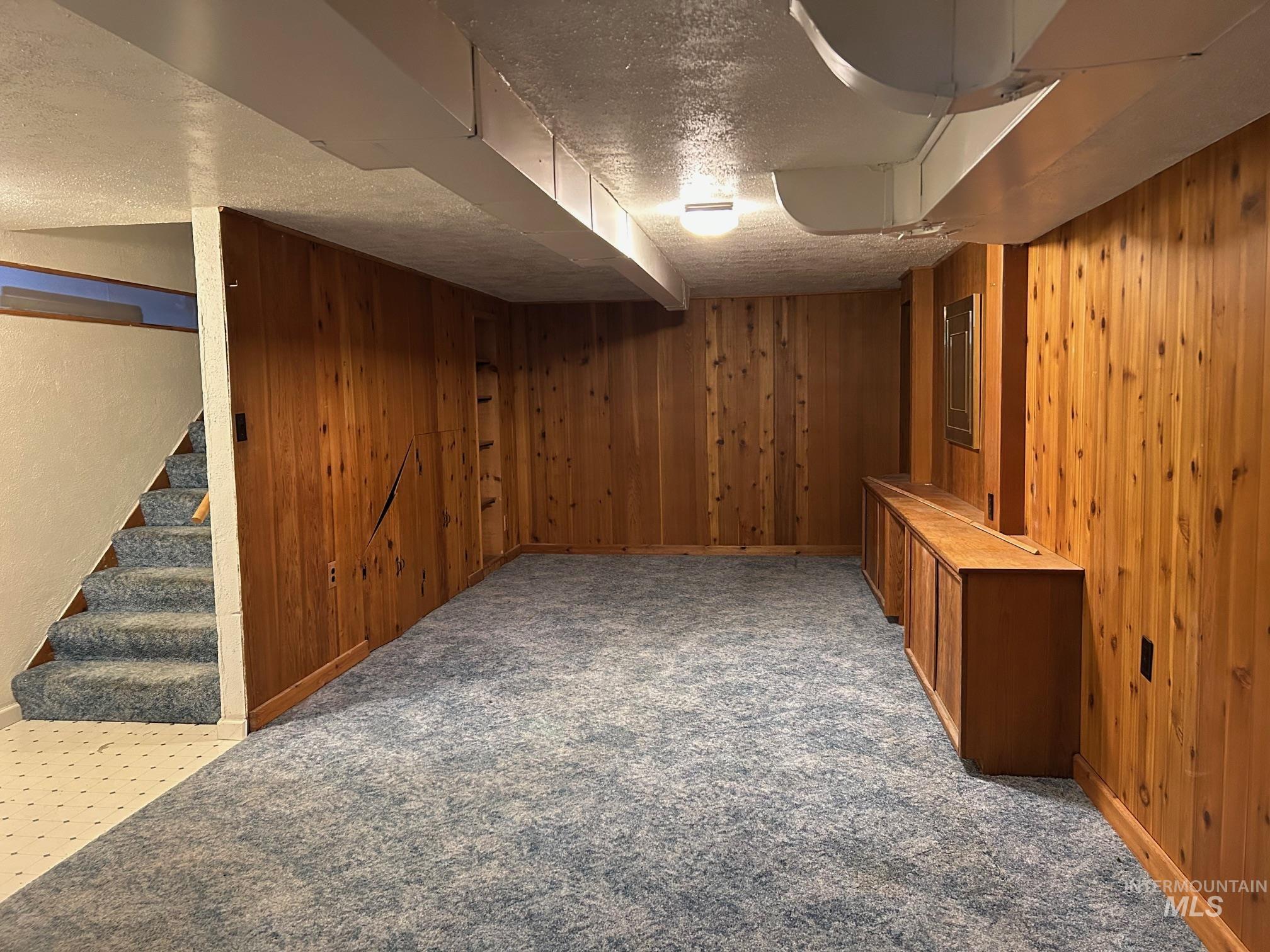 112 17th Avenue Lewiston, ID 83501 - Photo 26 of 40 Finished below grade area featuring wood walls, a textured ceiling, light carpet, and stairway