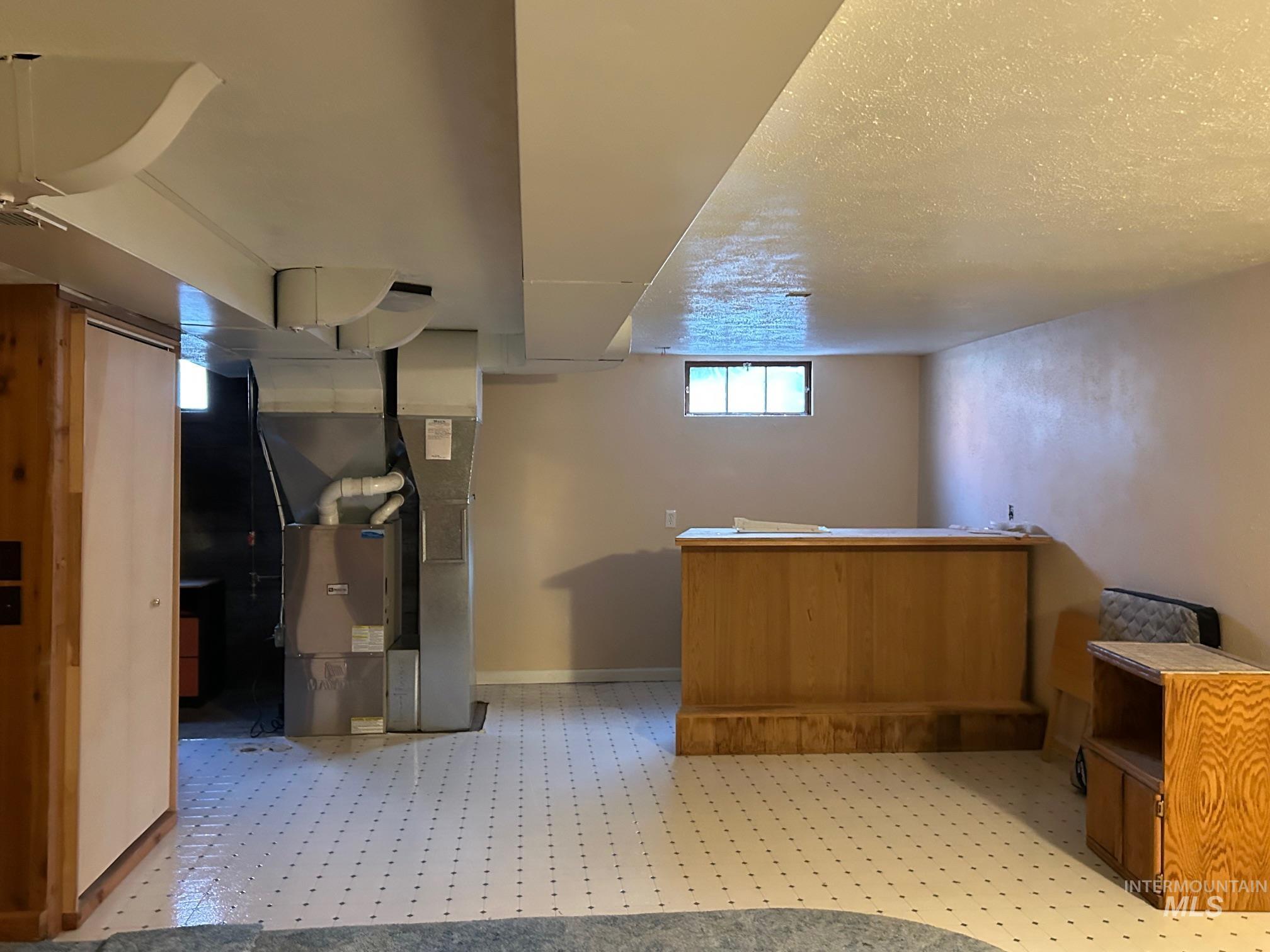 112 17th Avenue Lewiston, ID 83501 - Photo 27 of 40 Bar area featuring heating unit, brown cabinets, light flooring, and a textured ceiling