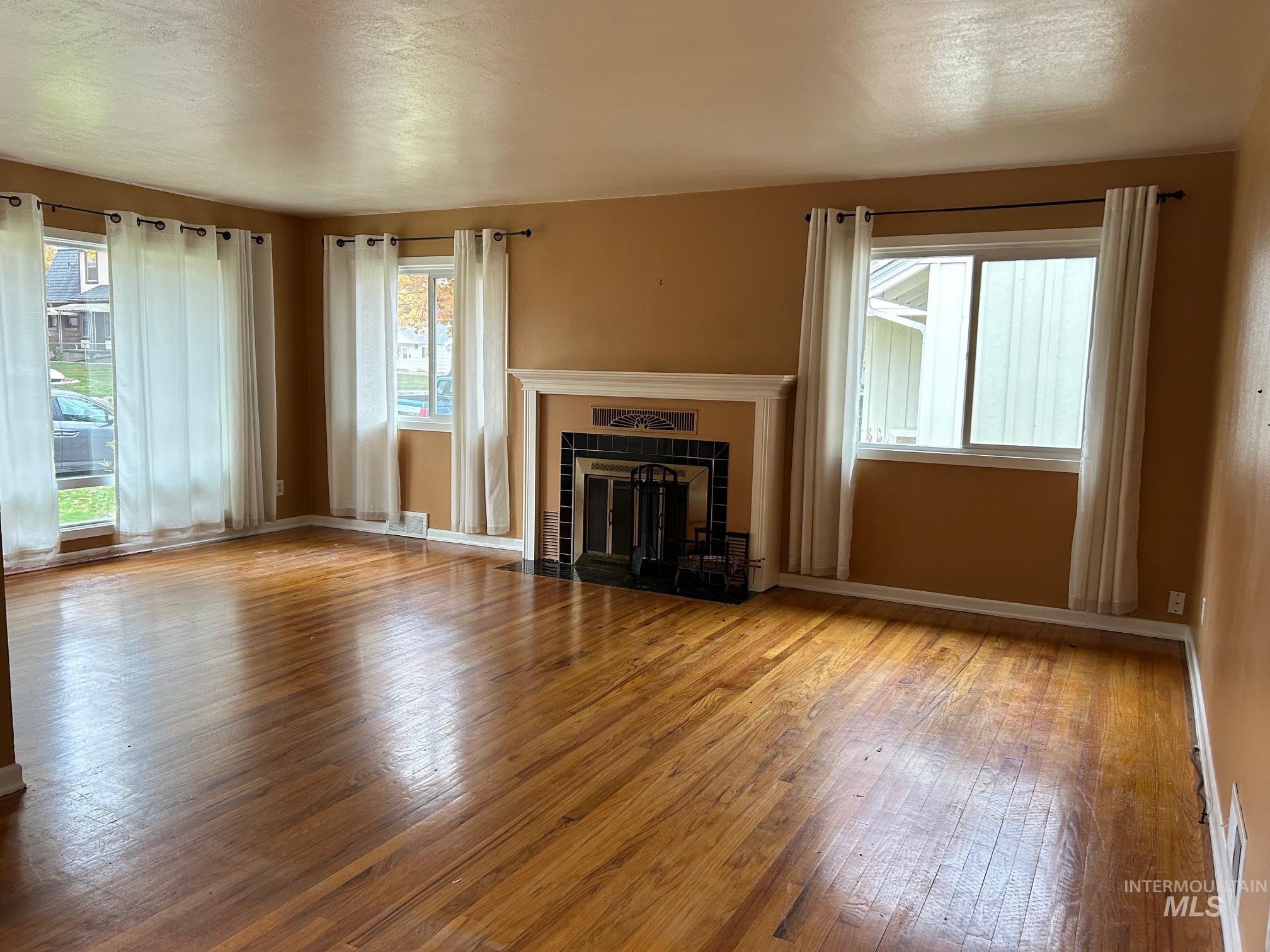 112 17th Avenue Lewiston, ID 83501 - Photo 4 of 40 Living room with a tiled fireplace, plenty of natural light, hardwood flooring, and a textured ceiling