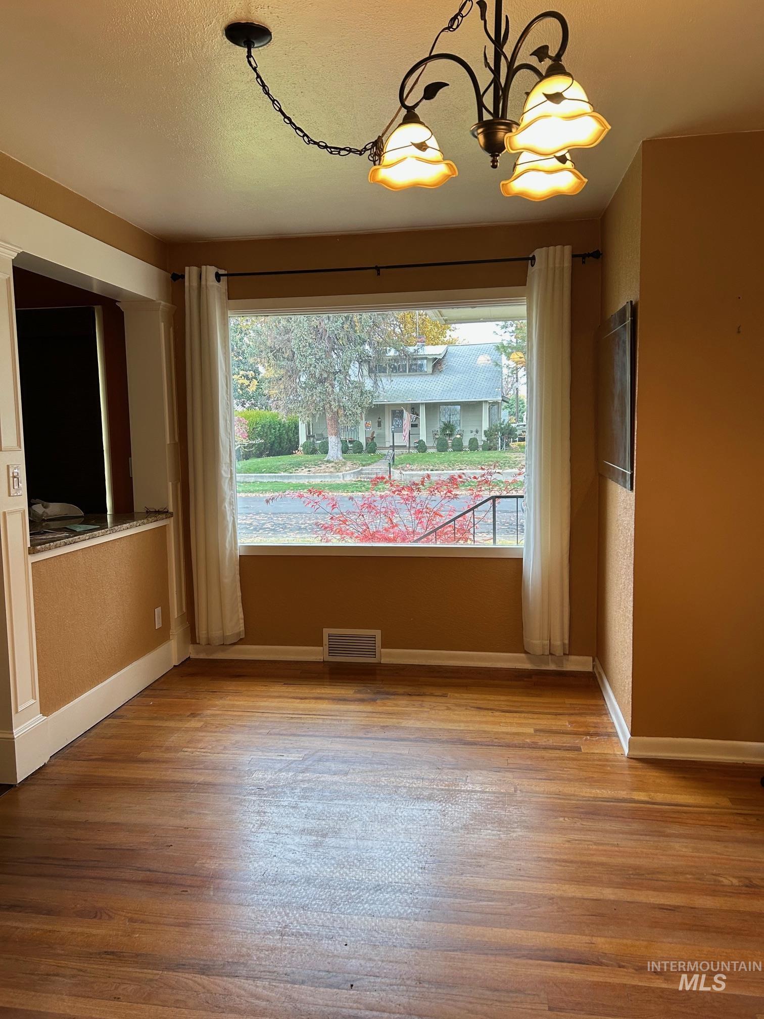 112 17th Avenue Lewiston, ID 83501 - Photo 6 of 40 Dining area featuring healthy amount of natural light, hardwood flooring, a textured ceiling, and a chandelier