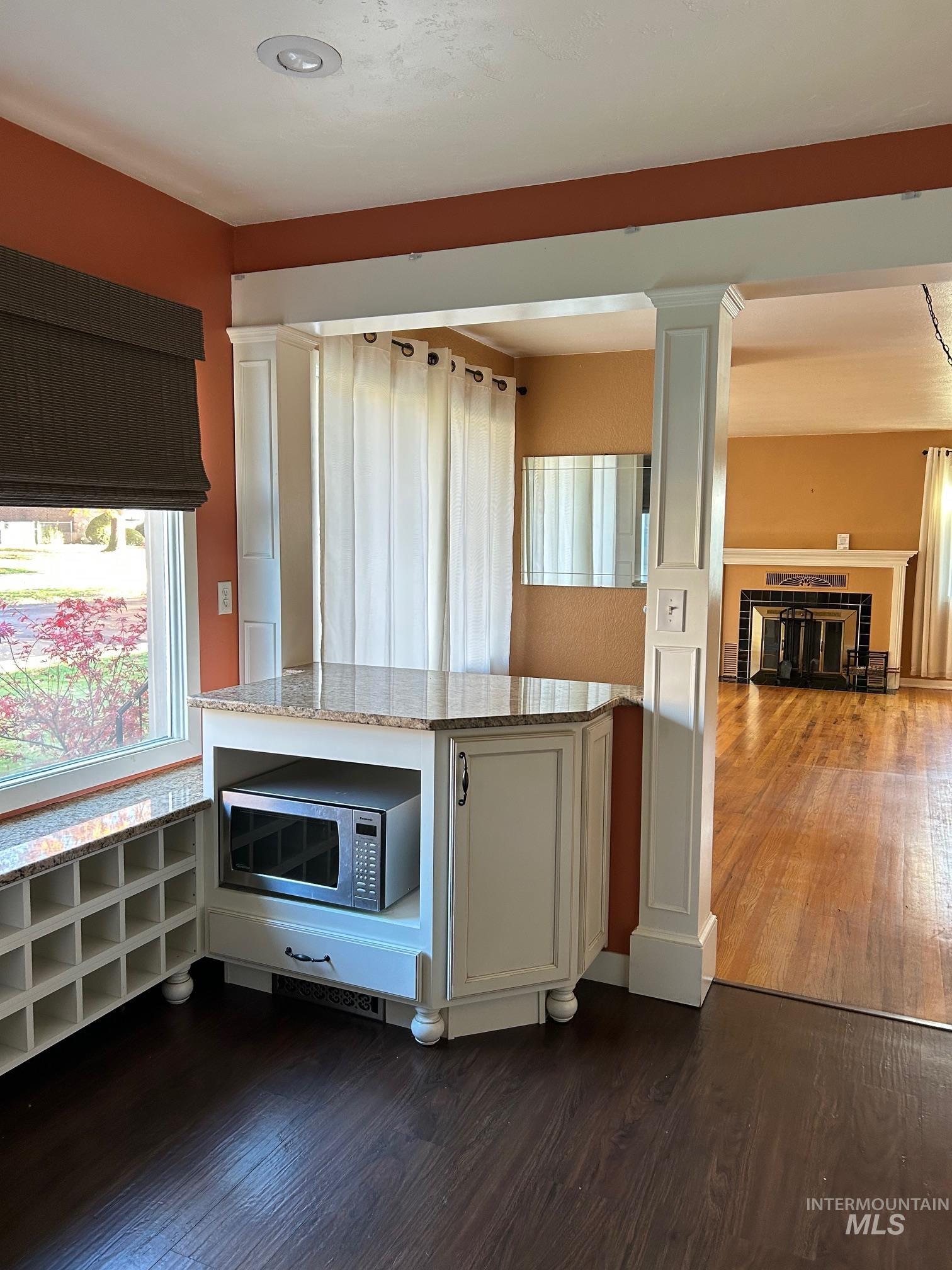 112 17th Avenue Lewiston, ID 83501 - Photo 10 of 40 Kitchen with white cabinets, light stone counters, dark wood-style flooring, stainless steel microwave, and decorative columns
