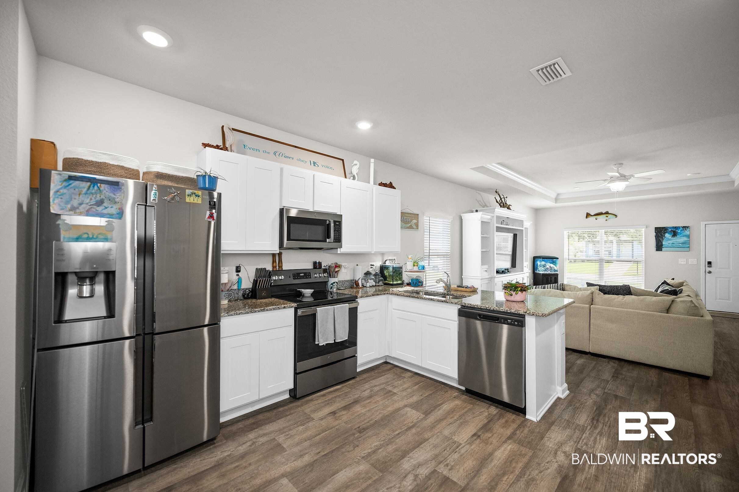 23997 Veranda Circle Elberta, AL 36530 - Photo 7 of 28 Open-concept kitchen featuring white cabinetry, stainless steel appliances, granite countertops, and wood-finish flooring