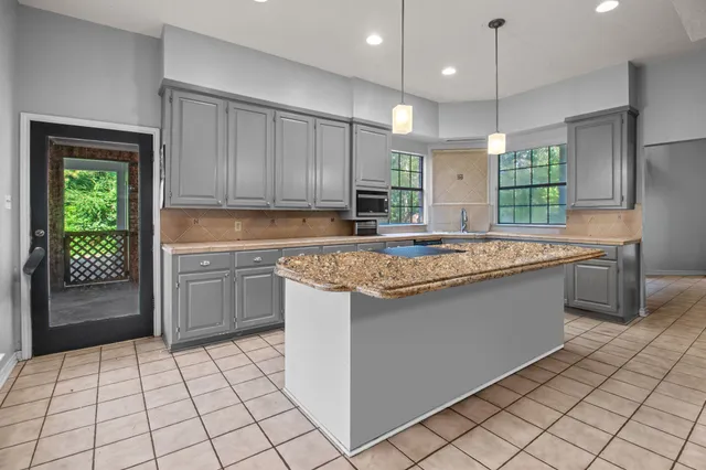 a kitchen with kitchen island granite countertop a sink a counter top space appliances and cabinets
