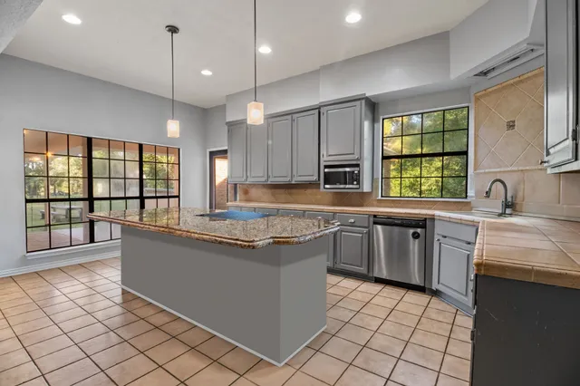 a kitchen with stainless steel appliances granite countertop a stove a sink and a microwave