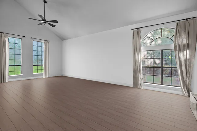 a view of an empty room with a window and wooden floor