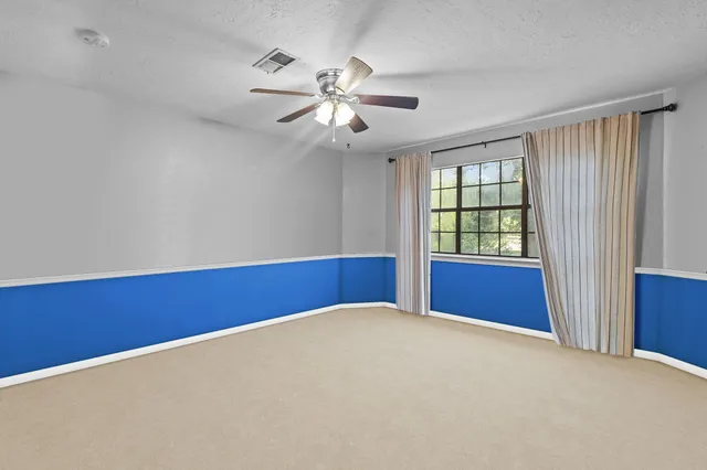 an empty room with windows and fan