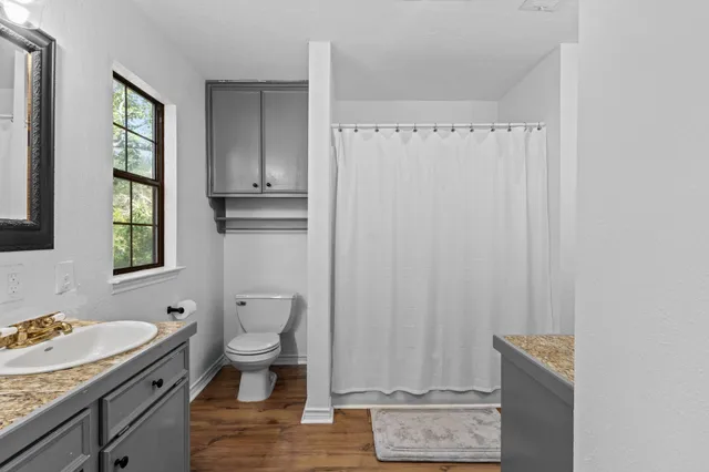 a bathroom with a granite countertop sink a toilet and a window