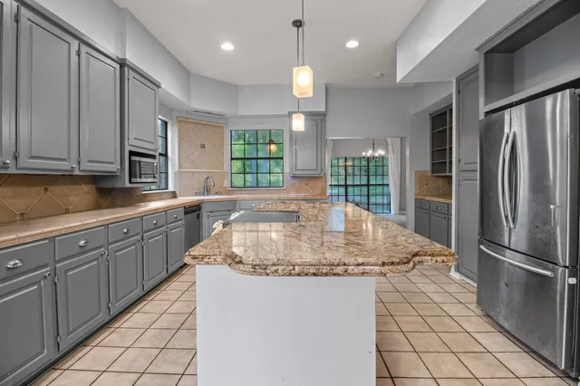 a kitchen with stainless steel appliances granite countertop a sink a stove a refrigerator and a granite counter tops with a window